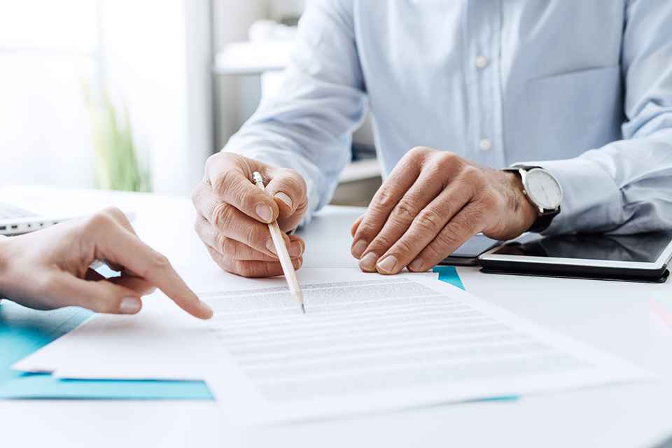 © StockPhotoPro - stock.adobe.com Foto: Person hält Stift und zeigt auf Formular