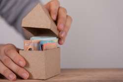 © vegefox.com - stock.adobe.com Foto: Schachtel in Hausform mit Geldscheinen