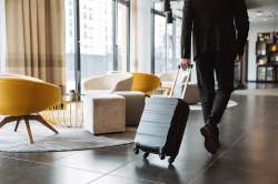 © Drobot Dean - stock.adobe.com Foto: Mann zieht Koffer in Hotellobby